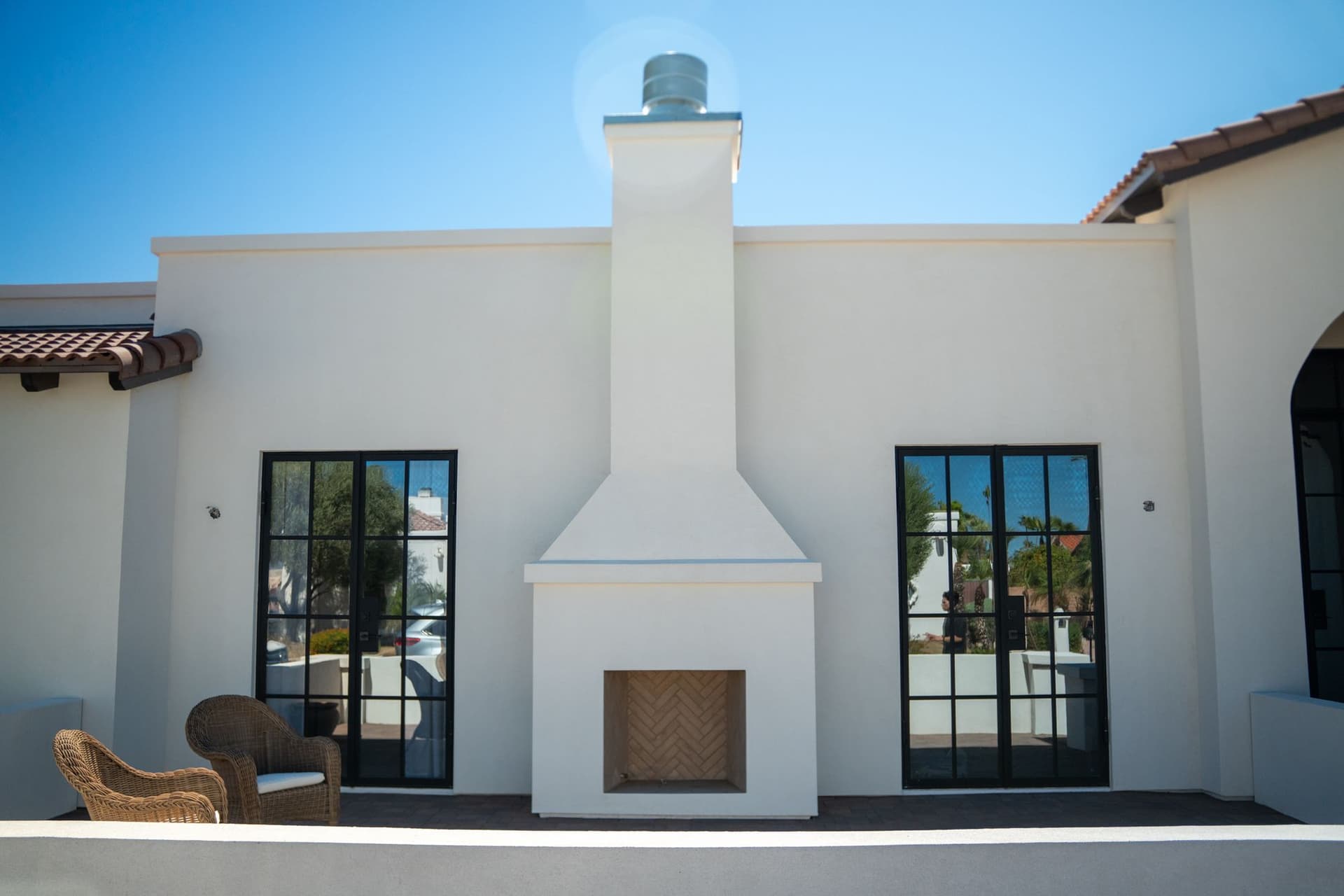 Completed exterior courtyard with a white stucco fireplace and black-framed glass doors