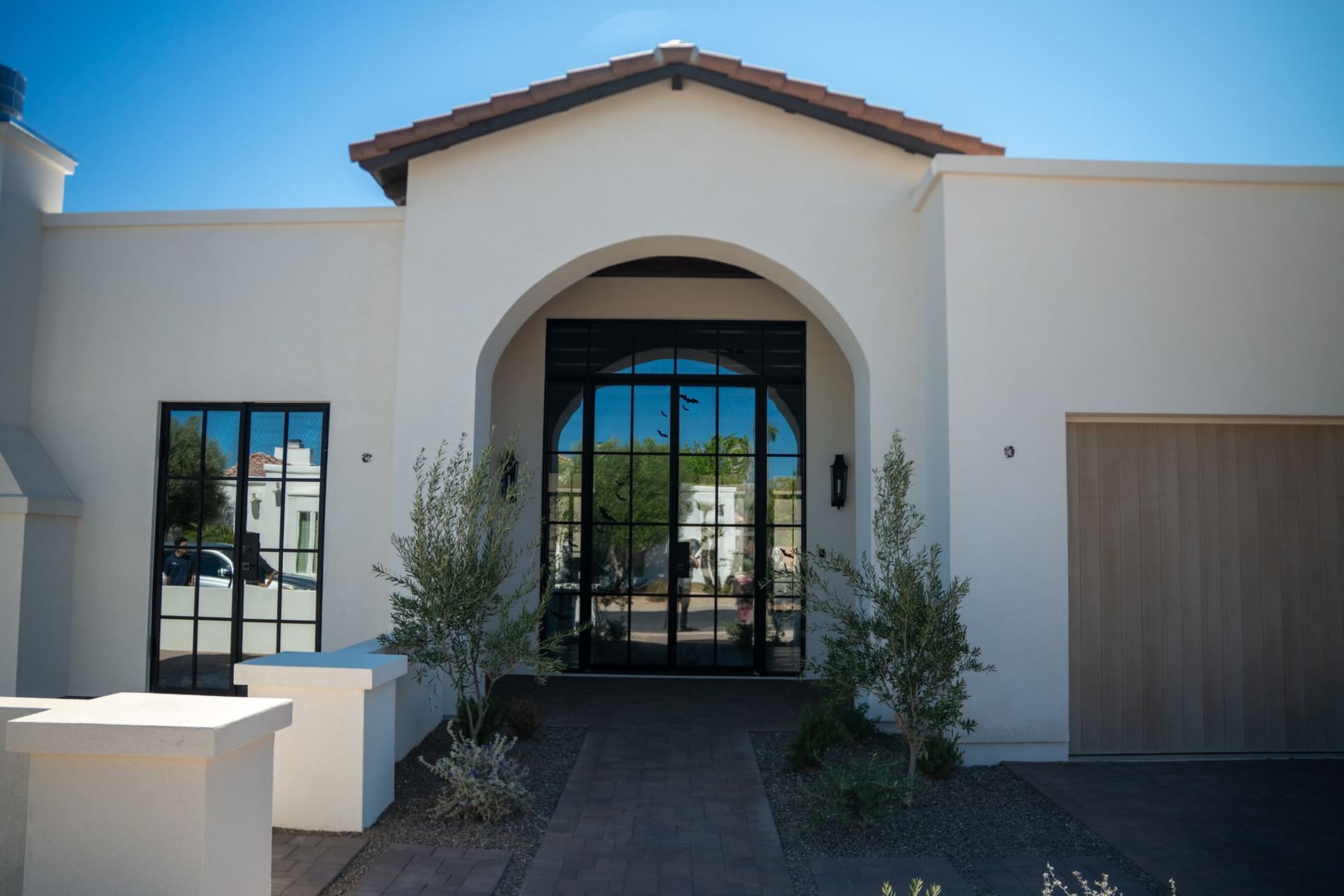 Completed home exterior with an arched white stucco entrance and wood garage door