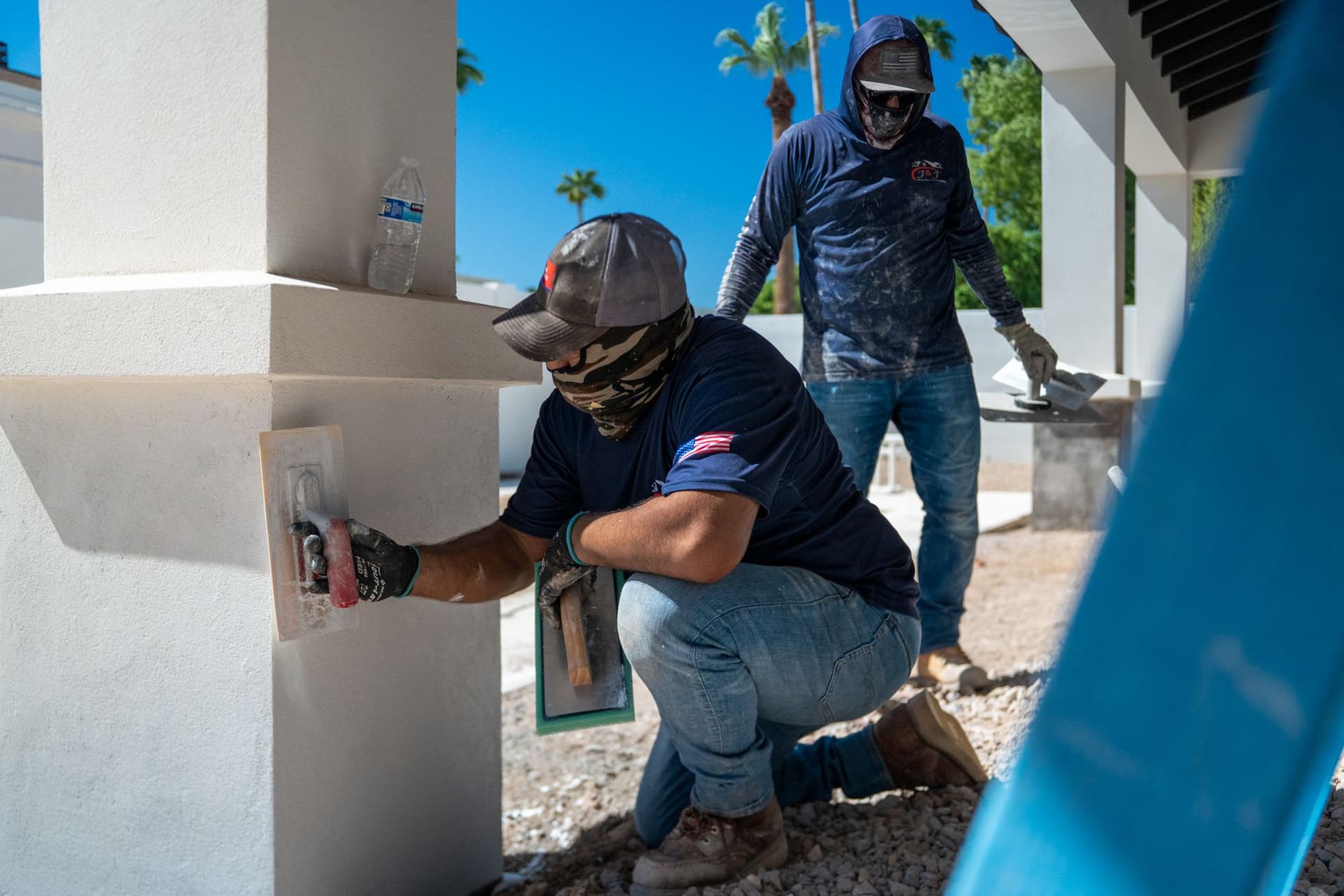 J&J Pros crew members finishing white stucco on exterior columns